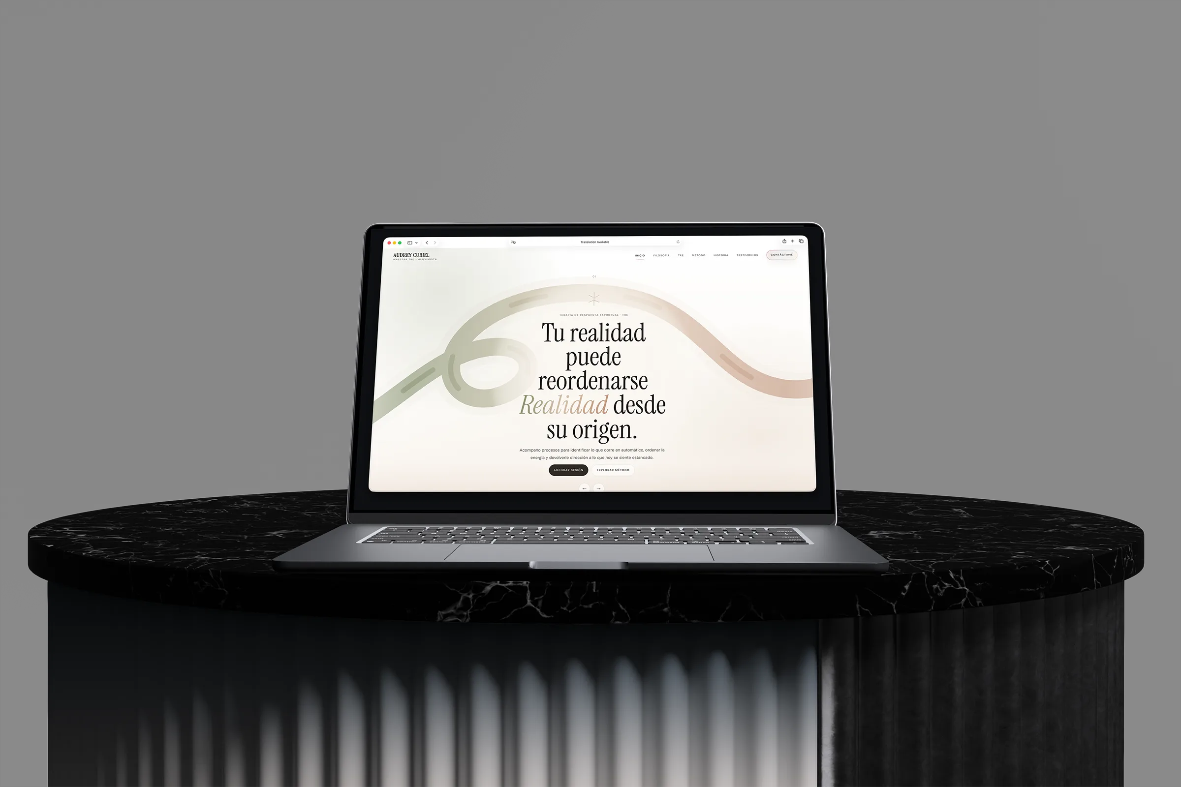 Audrey Curiel wellness website displayed on a laptop above a black marble pedestal.