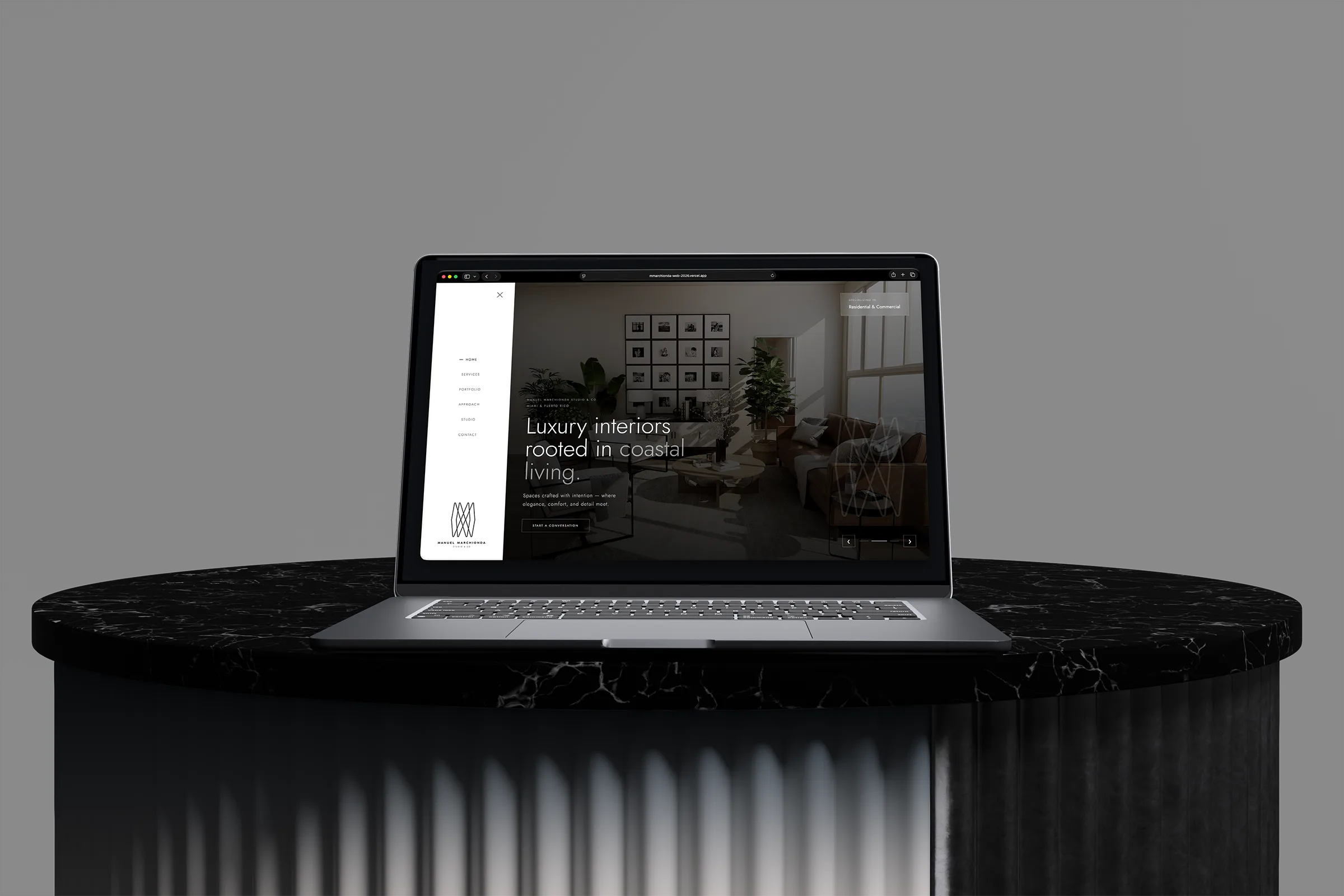 Manuel Marchionda Studio interior design website displayed on a laptop above a black marble pedestal.