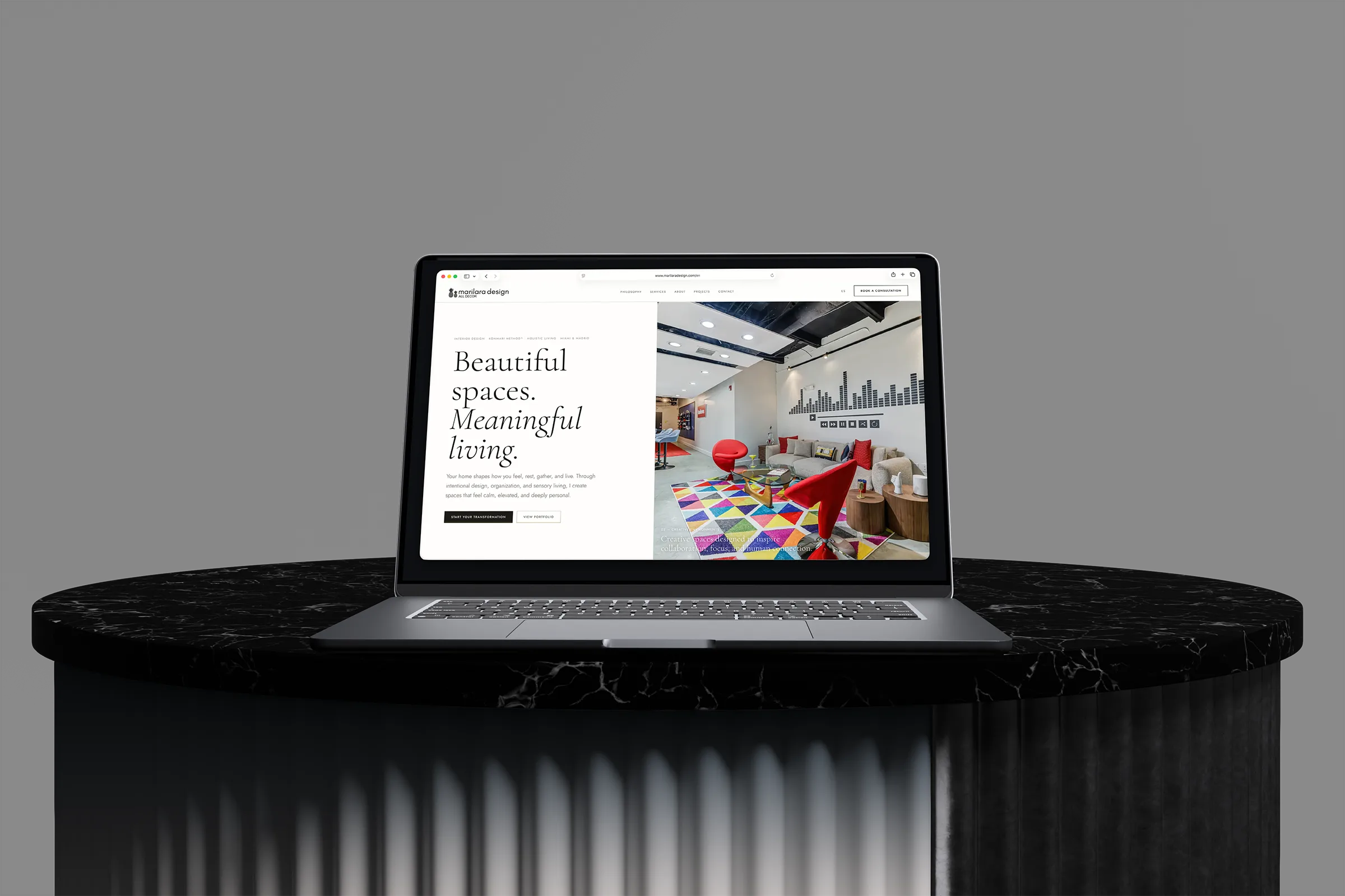 Marilara Design interior design website displayed on a laptop above a black marble pedestal.