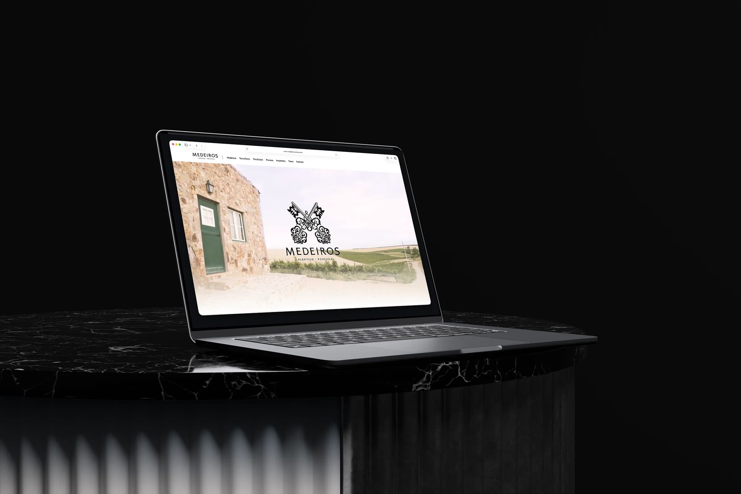 Medeiros Wines website displayed on a laptop above a black marble pedestal.