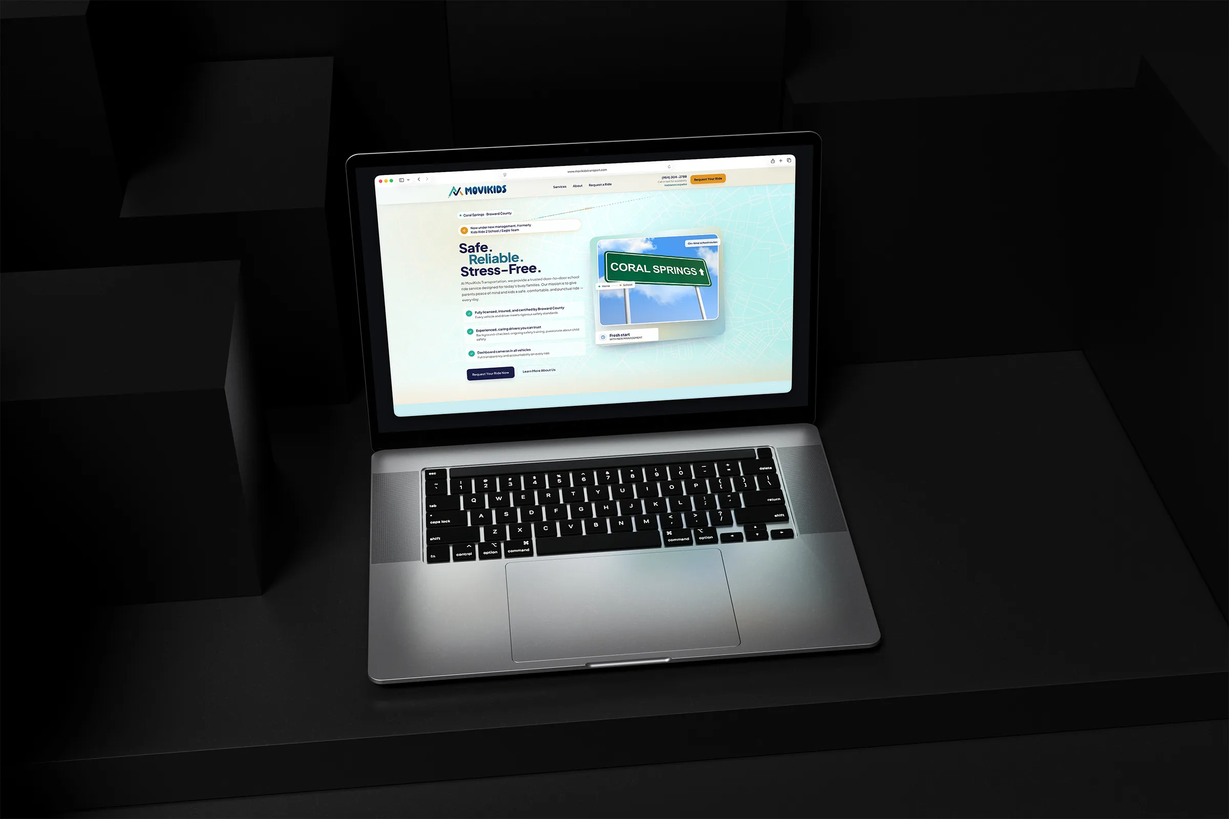 Movikids student transportation website displayed on a laptop in a dark geometric setting.